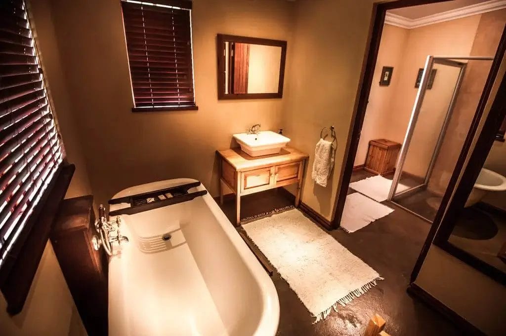 A warmly lit bathroom with a freestanding tub, wooden vanity, and walk-in shower.