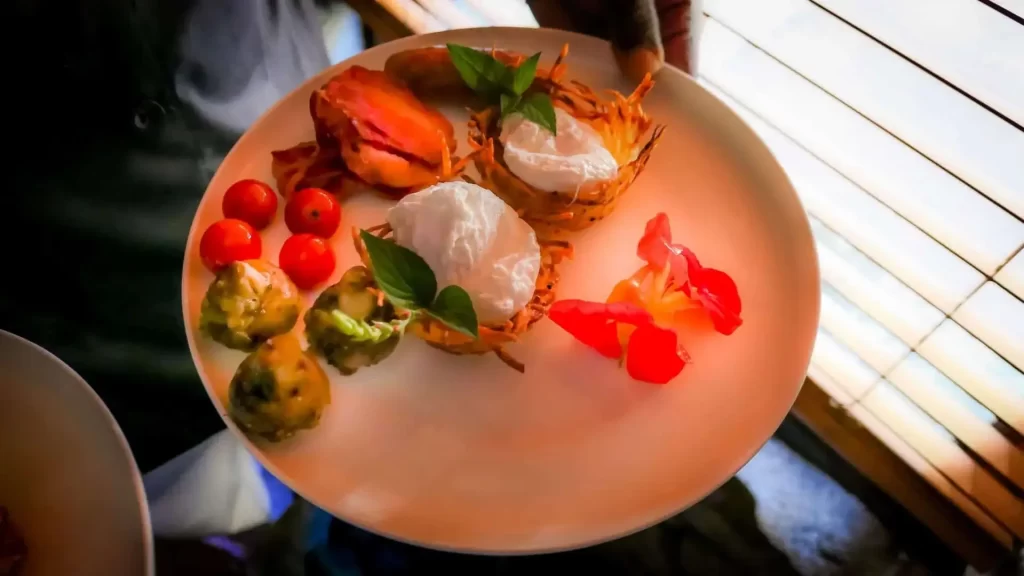 Plate of assorted gourmet appetizers with a poached egg, cherry tomatoes, and edible flowers.