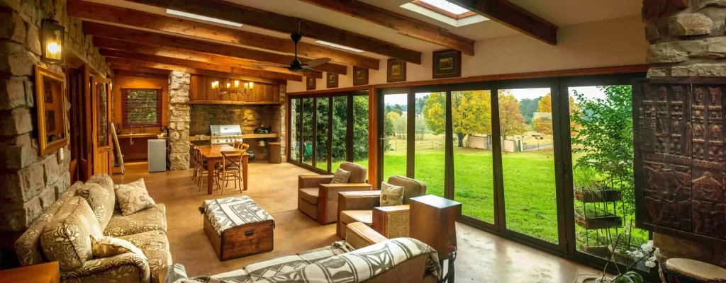 Spacious living room with rustic decor and large windows overlooking green outdoors.