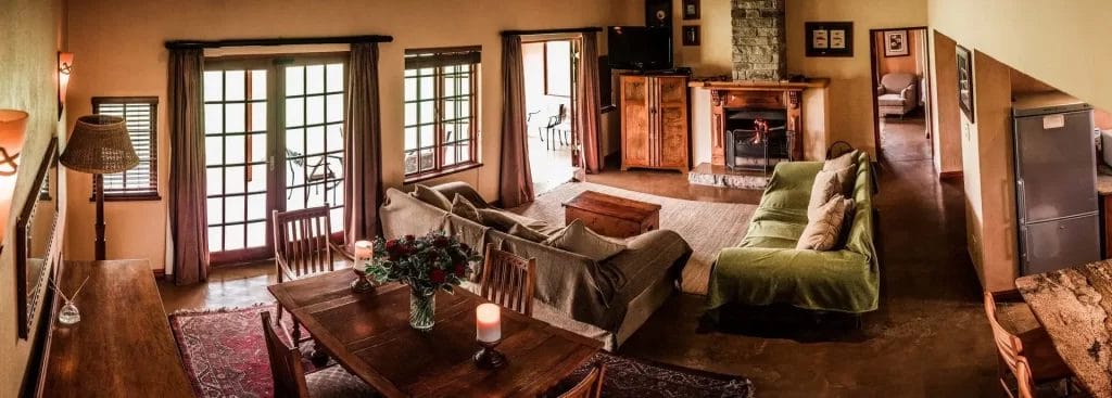 Cozy and warmly lit living room interior with comfortable furniture, a fireplace, and open french doors.