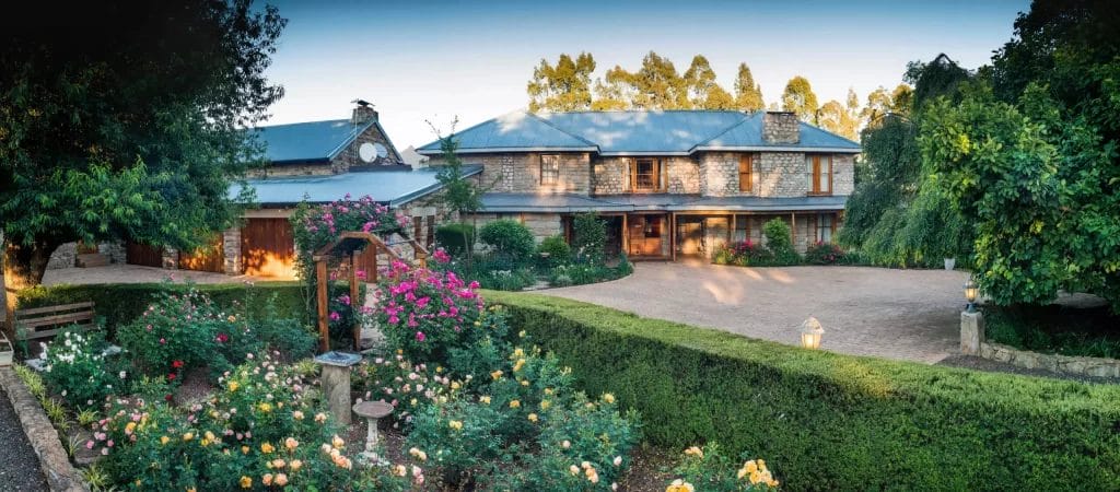 Panoramic view of a sprawling estate with manicured gardens at dusk.