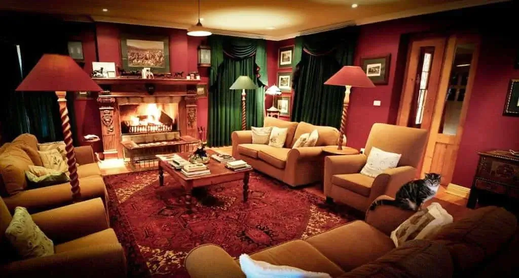 A cozy, traditional living room with a fireplace, warm lighting, and richly colored decor.