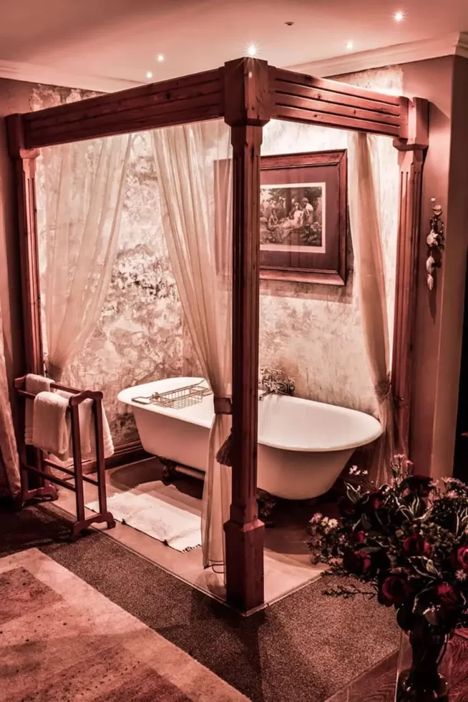 Elegant bathroom with freestanding bathtub, sheer curtains, and warm lighting.