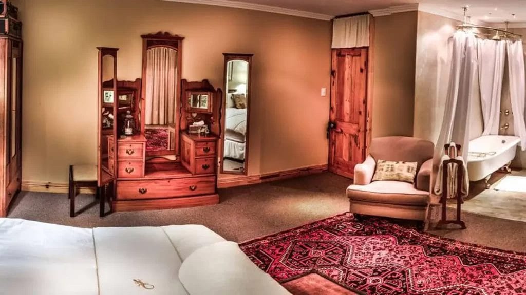 Elegant bedroom with antique furniture and a freestanding bathtub.