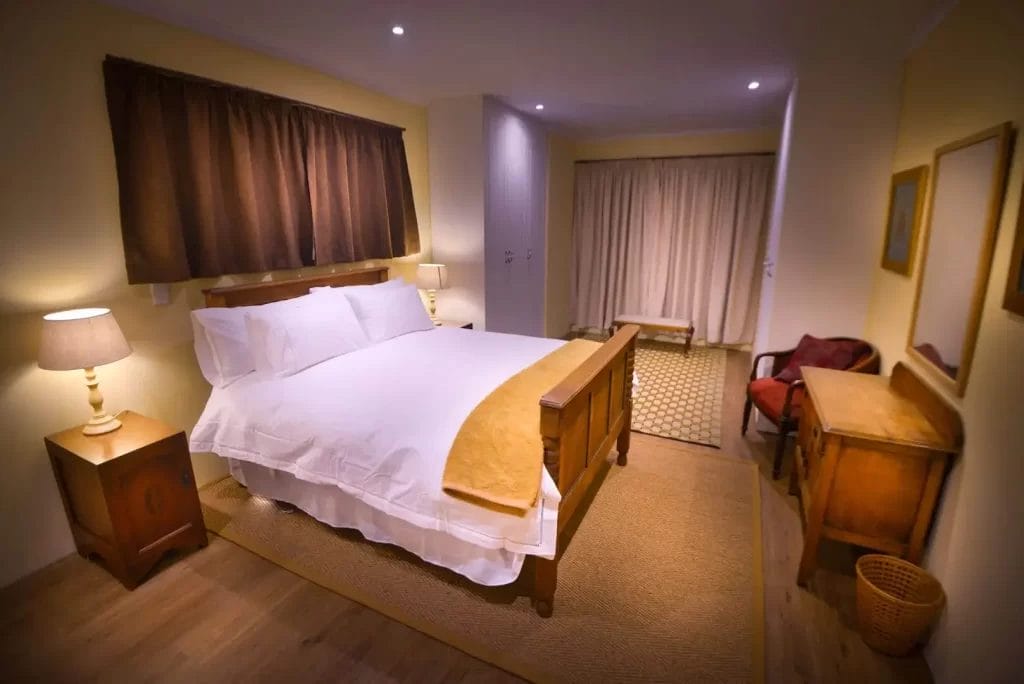 Well-appointed hotel room with a neatly made bed, warm lighting, and wooden furnishings.